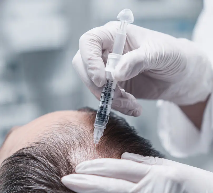 Experienced doctor in white coat signing documents or filling forms under desk lamp in dark office
